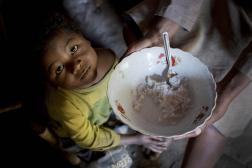 Photo of a young girl looking up at a bowl of porridge. 